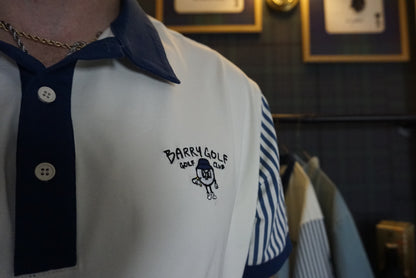 A close-up of a person wearing a white polo shirt with a navy blue collar and placket, featuring a navy blue embroidered logo that reads 'BARRY GOLF, GOLF CLUB' with a small golf ball character. The right sleeve has navy blue and white vertical stripes.